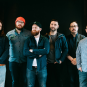 Artist the wonder years standing in front of dark green wall